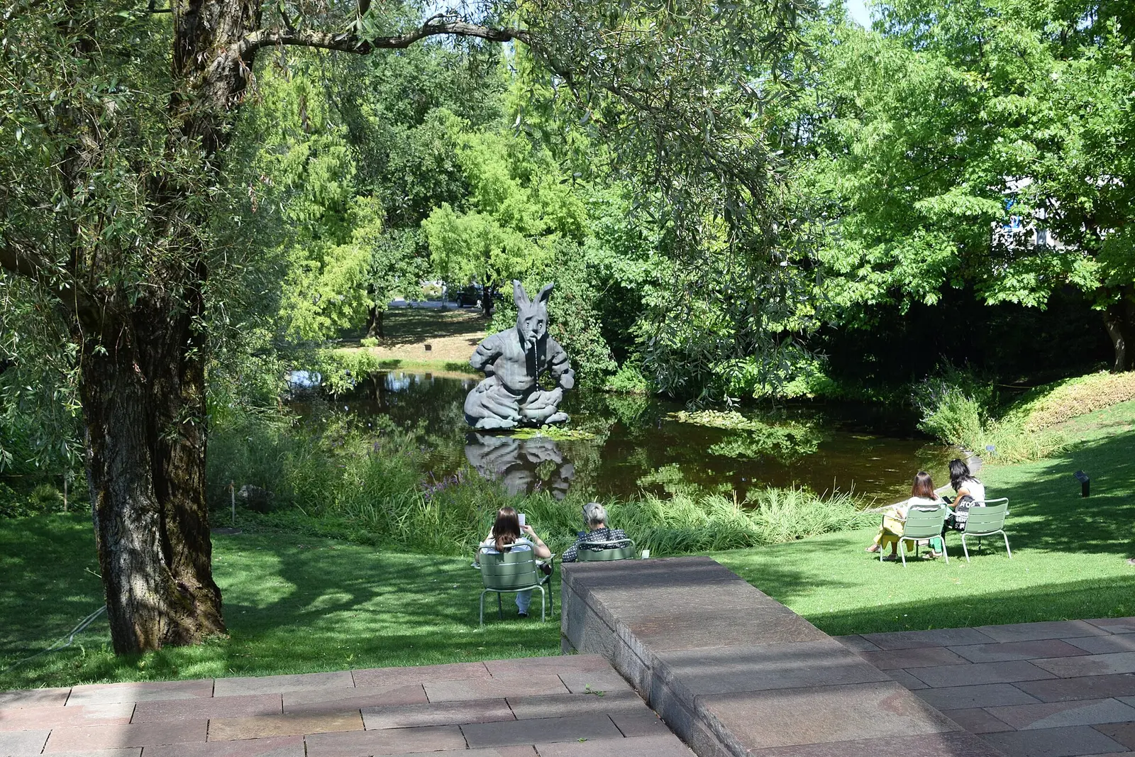 Visitors on the lawn beside the pond in the Fondation Beyeler park