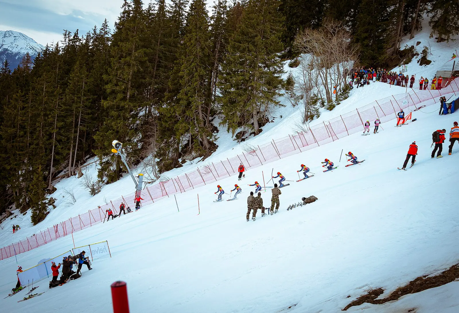 Skiers and officials on a snowy race slope at the Crans-Montana women's World Cup