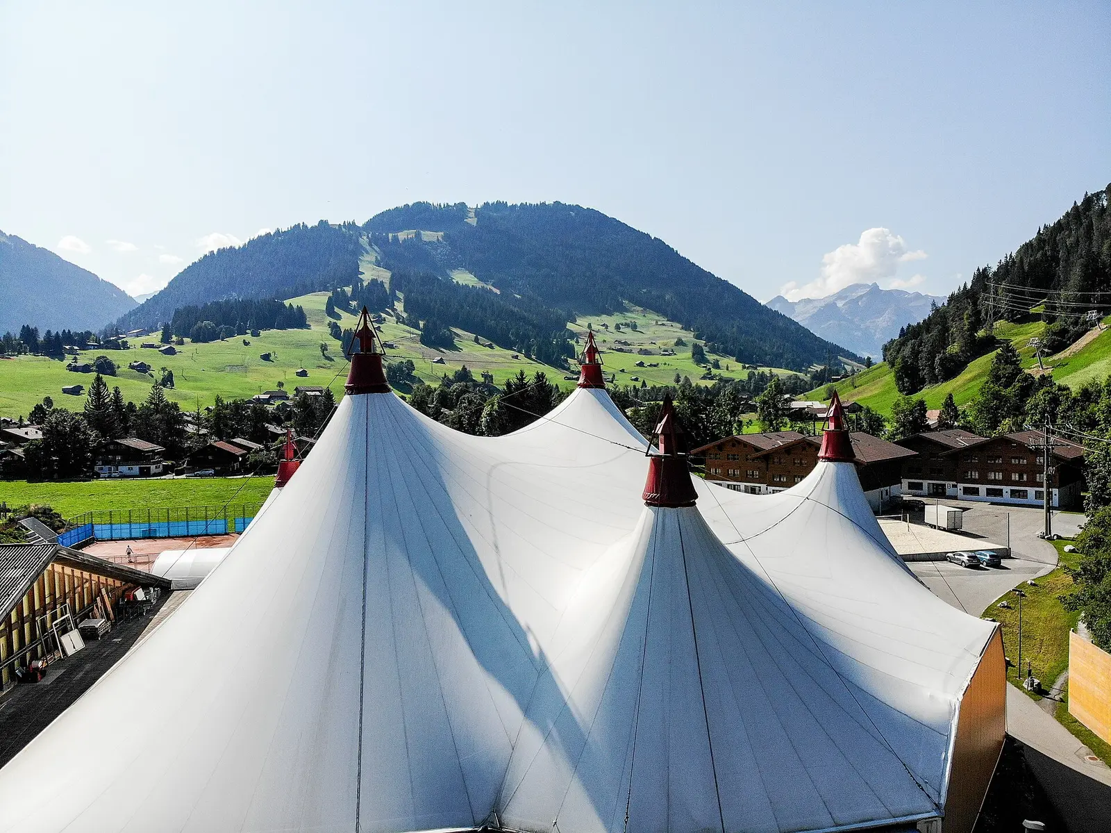 White festival tent in Gstaad with green Alpine hills behind
