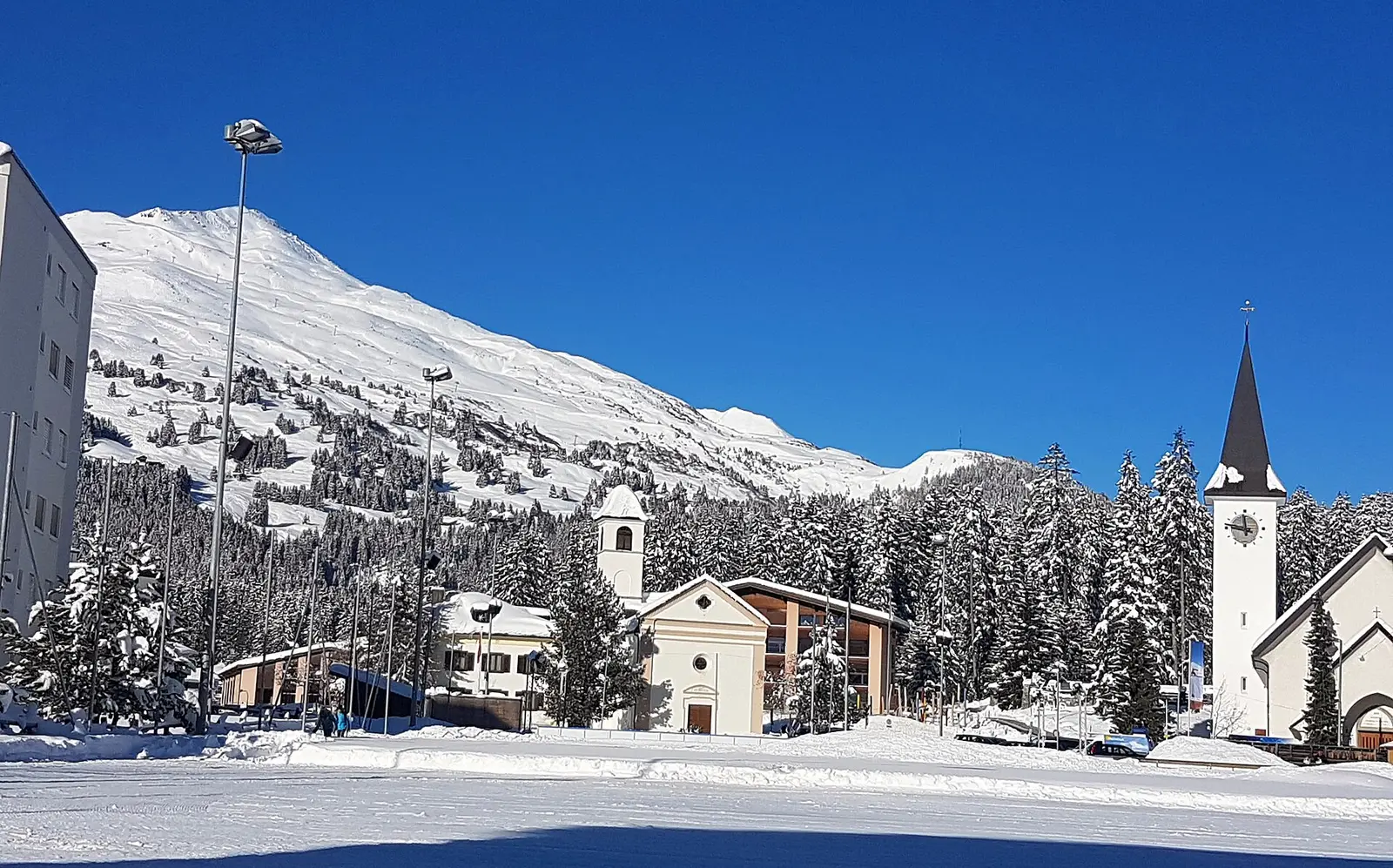 Snowy Lenzerheide village with church and mountain slopes