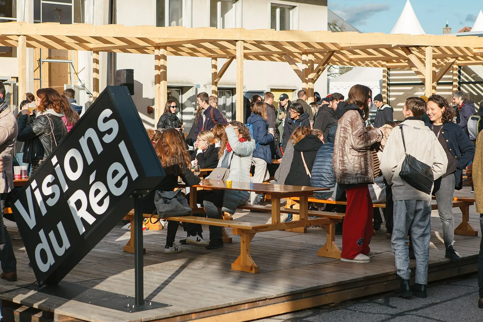 Visitors gathered at tables on the Place du Reel terrace during Visions du Reel in Nyon