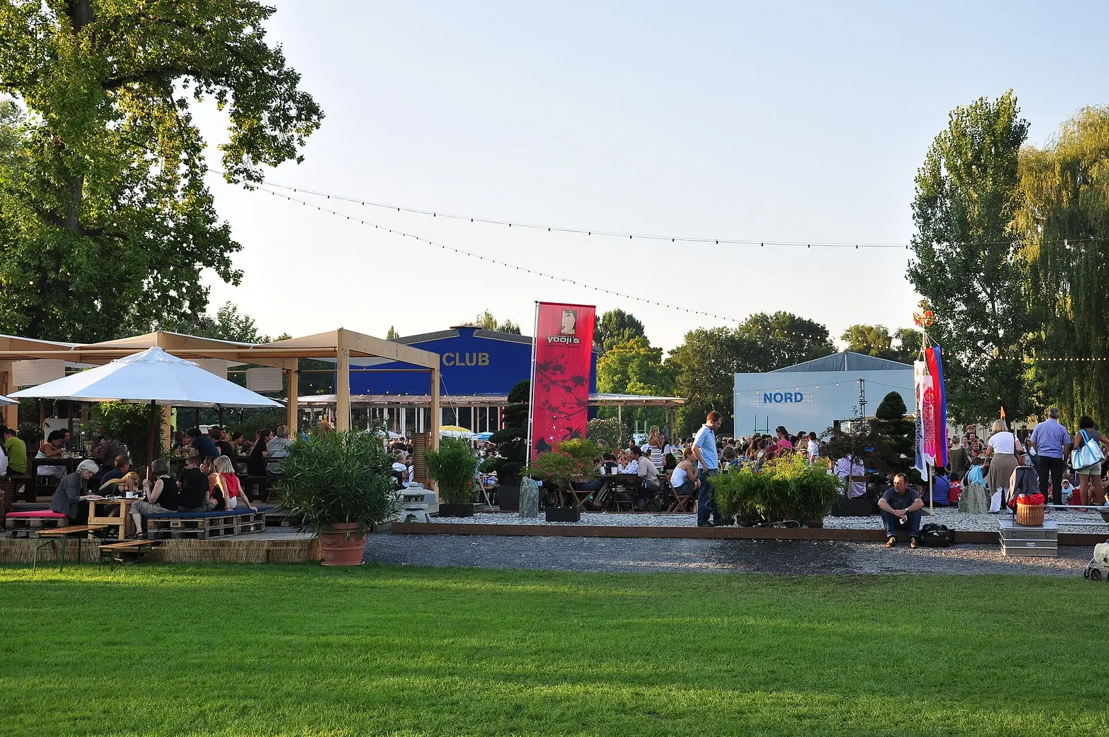 Lakeside festival grounds with food stalls and trees at the Zurich Theater Spektakel